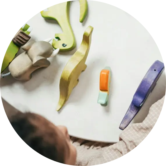 Niña jugando con figuras de animales de madera sobre una mesa