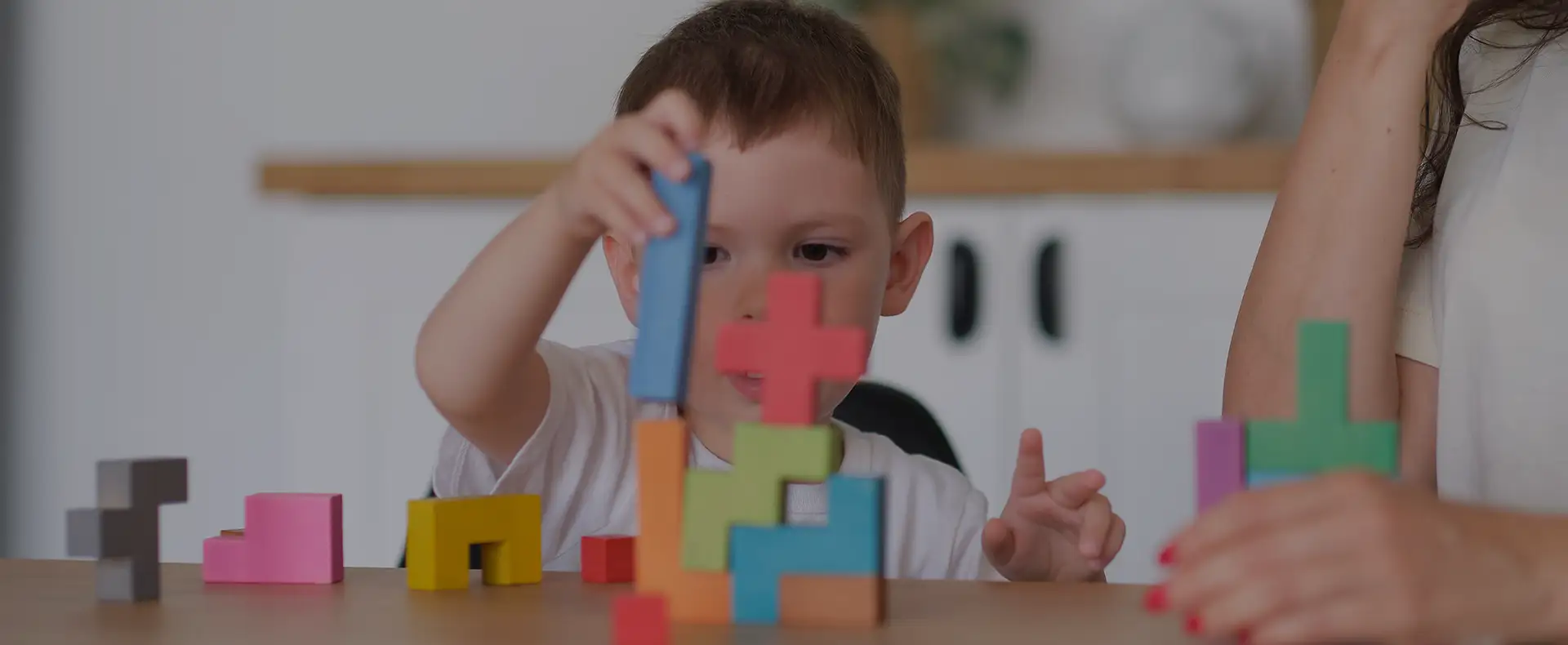 Niño jugando con bloques de construcción de colores junto a un adulto